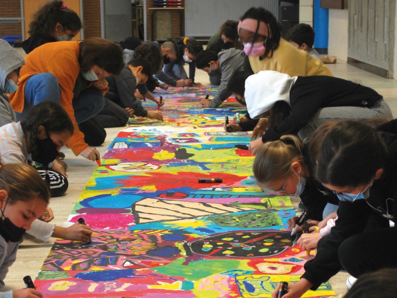 Les enfants peignent ensemble un grand tableau coloré