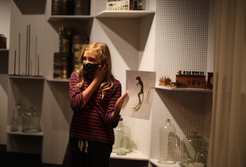 Meisje staat voor museumvitrine vol wetenschappelijke voorwerpen