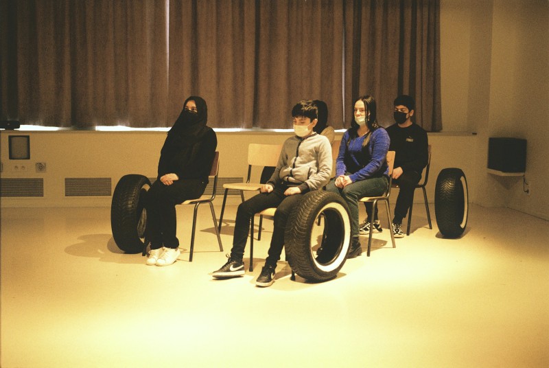 arrangement de chaises et de pneus de voiture, certains jeunes s'assoient sur les chaise.