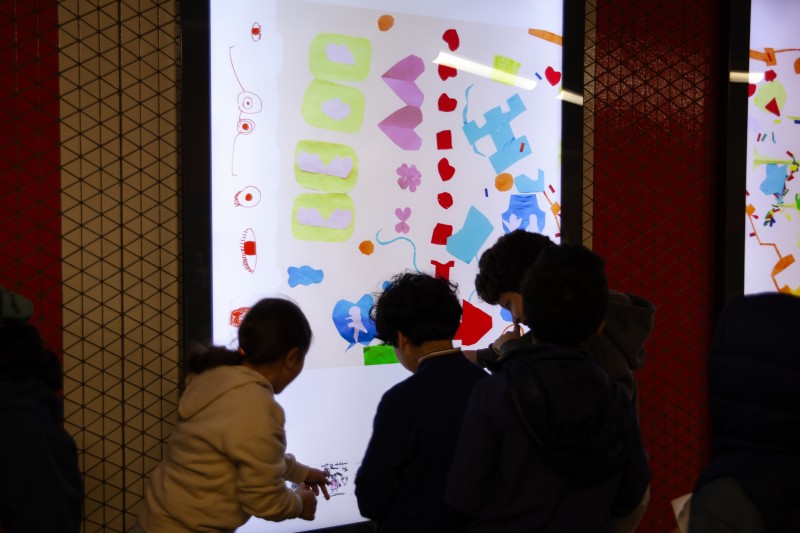 kinderen kijken naar de presentatie van hun werken