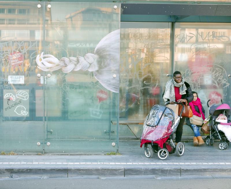 Een vrouw met buggy wacht aan een tramhalte waar een kunstwerk op aangebracht werd