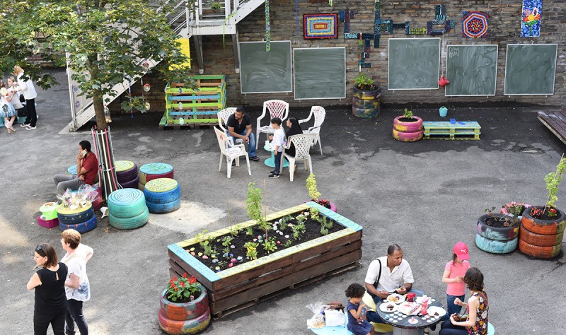 Fête d'école, dehors. Les parents se baladent parmi les bacs de plantes que Boris a fabriqués avec les enfants.