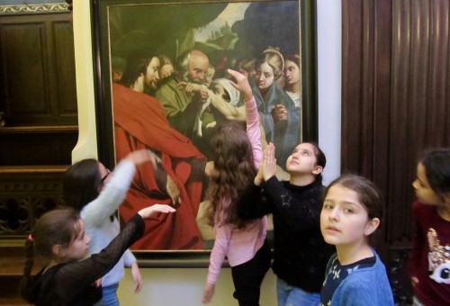 Kinderen springen rond barok schilderij in museumruimte